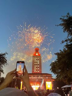 people are taking pictures with their cell phones as fireworks go off in the sky above them