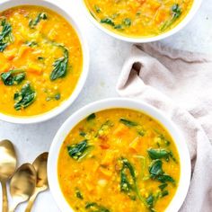 three bowls of soup with spinach, carrots and cheese on the side next to a spoon