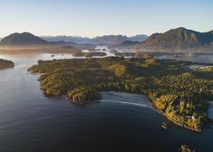 an aerial view of several small islands in the water with mountains in the background and foggy sky