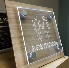 an illuminated restroom sign on top of a wooden table