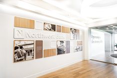 an office with wooden floors and pictures on the wall in front of glass partitions