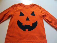 an orange shirt with black pumpkin faces on it