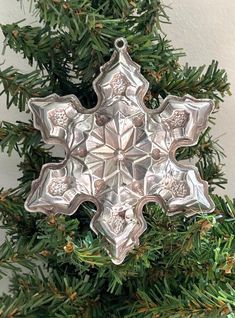 a silver snowflake ornament hanging from a christmas tree