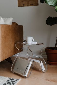 a glass coffee table sitting on top of a hard wood floor next to a couch