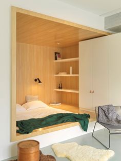 a bedroom with a bed, chair and bookshelf in the corner next to it