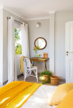 a bedroom with yellow and white bedding, mirror, desk and chair in it