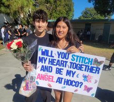 two people holding flowers and a sign that says will you stitch my heart together and be my angel at hoo?