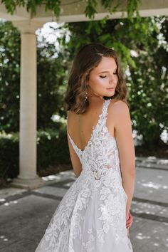 a woman in a wedding dress standing under a pergolated roof with her back to the camera