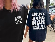 "✦ 🇺🇸SENT TO PRODUCTION AND PRINTED IN THE US🇺🇸 ✦The perfect In My Band Mom Era Graphic TShirt is yours!  ✦ QUICK FACTS ✦ Comfort Colors® C1717 T-Shirt is 100% ringspun cotton (ringspun=comfort) Preshrunk, soft washed, garment-dyed fabric Twill-taped back neck and shoulders ✦ SIZING TIPS ✦ All our garments are UNISEX.  FOR AN OVERSIZED LOOK, SIZE UP 2-3 SIZES For a Relaxed Fit order your Usual Size For a Snug Fit order 1 Size down If you're unsure: Lay your favorite fitting T-Shirt flat and *measure armpit to armpit (1\" under armpit) for width *measure from point where neck seam meets shoulder all the way to bottom for length & compare with measurements in Size Chart provided in each listing *Please note, Size Chart Measurements are to be used as guidelines and measurements may vary w Letter Print Shirt For Concerts And Music Festivals, Band Merch Shirt With Slogan For Concerts, Band Merch Shirt With Slogan For Fans, Band Merch Shirt With Text Print For Concert, Band Merch Slogan Shirt For Fans, Band Merch Shirt With Slogan, Concert Shirt With Slogan In Relaxed Fit, Cotton Slogan Shirt For Concert, Relaxed Fit Slogan Shirt For Concert