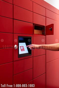 a hand is pressing the button on a red wall mounted mailbox that has an email envelope in it