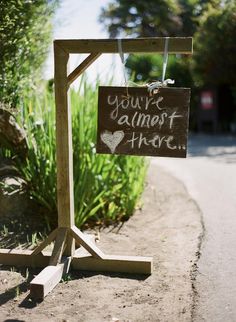 a sign that says you're almost here on the side of a road in front of some bushes