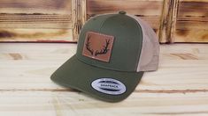 Deer hunter hat with precision leather etched patch with optional . The hats are the popular retro trucker style YP 6-panel snap-back that look great and are available in several colors - see available colors. Optional patch color: Light Brown Dark Brown Rawhide Hat Details: SIZE - Adult size with snap closure - One size fits most. DESIGN - Custom laser etched American flag patch with machine sewn edge MATERIAL - 65% polyester and 35% cotton. Vegan Friendly Leather Patch (Leatherette). SHIPS - I Classic Trucker Hat With Flat Bill For Outdoor, Rugged Outdoor Hat With Leather Patch, Western Style Baseball Cap With Flat Bill For Outdoor, Western Style Snapback Hat For Outdoor, Six-panel Baseball Cap With Leather Patch For Outdoor, Western Style Snapback Trucker Hat For Outdoor, Western Snapback Hat With Flat Brim For Outdoors, Outdoor Six-panel Baseball Cap With Leather Patch, Casual Hunting Hat With Flat Brim