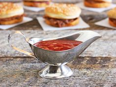 a silver gravy dish filled with sauce next to mini hamburgers on napkins