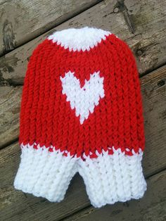 a red and white knitted hat sitting on top of a wooden table