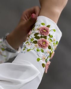 a close up of a person's arm wearing white pants and pink flowers on it