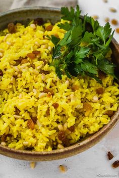 a bowl filled with yellow rice and garnished with parsley on the side