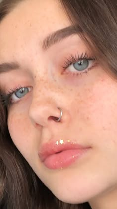 a close up of a person with freckles on her nose and nose ring