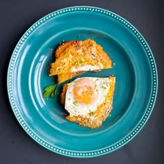 a blue plate topped with an egg and bread sandwich on top of a black table