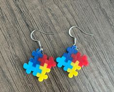 the earrings are made out of plastic and have multicolored puzzle pieces on them