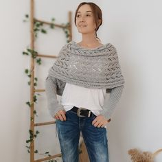 a woman standing in front of a ladder with her hands on her hips, wearing a gray knitted shawl