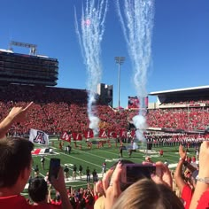 people taking pictures with their cell phones at a football game as fireworks go off in the air