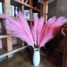 pink feathers in a white vase on a table