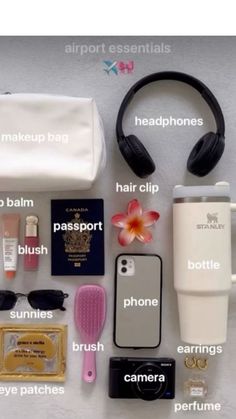 the contents of a travel bag laid out on top of a white table with headphones and other items