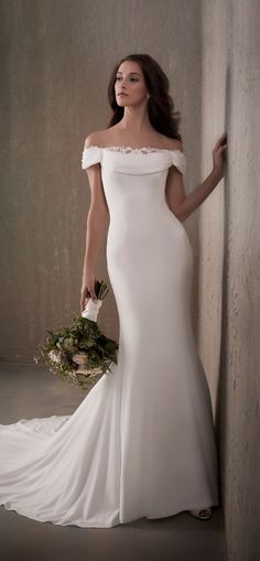 a woman in a wedding dress leaning against a wall