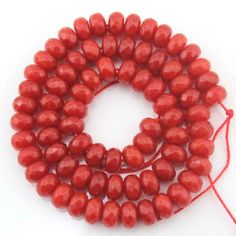 the beads are red and have been strung on a white surface with an orange string