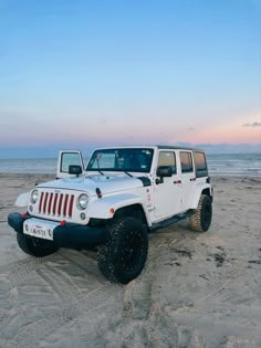 two white jeeps are parked on the beach