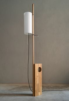 a wooden floor lamp with a white shade on it's side and a wood base