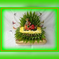 an arrangement of flowers and figurines on a wooden box with green border around it