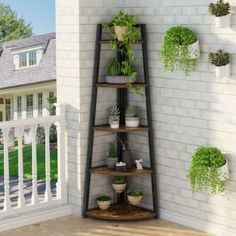 a corner shelf filled with potted plants next to a white brick wall in front of a house