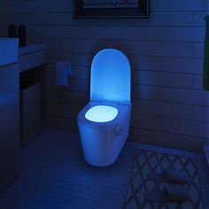 an illuminated toilet in the middle of a bathroom with blue lighting on it's side