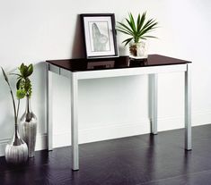 a table with two vases on it next to a white wall and black floor