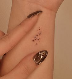 a woman's hand with a small tattoo on her left wrist and the moon in the background