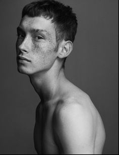 a shirtless man with freckles on his face is posing for a black and white photo