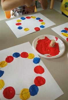 two paper plates with red, yellow and blue circles on them sitting on a table