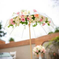 an umbrella decorated with flowers and greenery on a patio table in front of a house