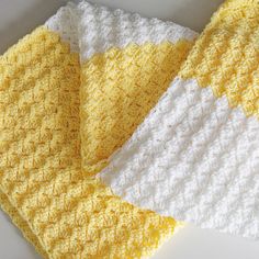 two yellow and white crocheted blankets laying next to each other