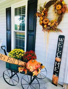 a wheelbarrow filled with pumpkins and flowers on the front door of a house