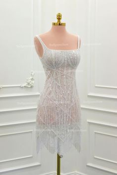 a mannequin dressed in white sequins and beaded dress on display