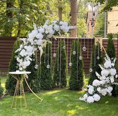 an outdoor wedding ceremony with white flowers and greenery on the side of the fence