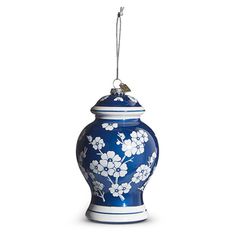 a blue and white vase with flowers hanging from it's side on a white background