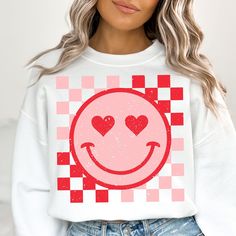 a woman wearing a white sweatshirt with red hearts on the front and checkered background