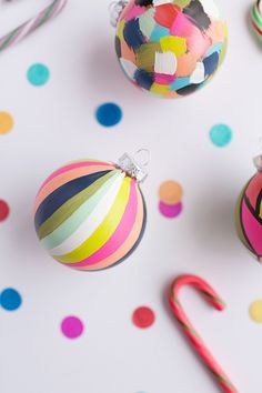 colorful ornaments and candy canes on a white surface with confetti around them