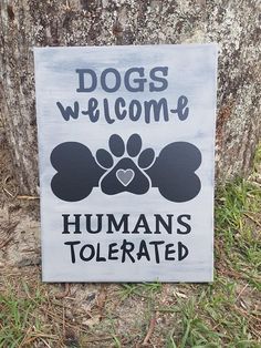 a sign that says dogs welcome humans tolerated on the side of a tree