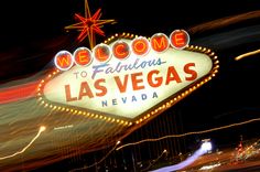 the welcome to fabulous las vegas sign lit up at night with lights in the background