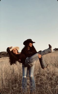 two women are standing in the middle of a field