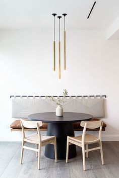 a dining room table with four chairs and a vase on the table in front of it